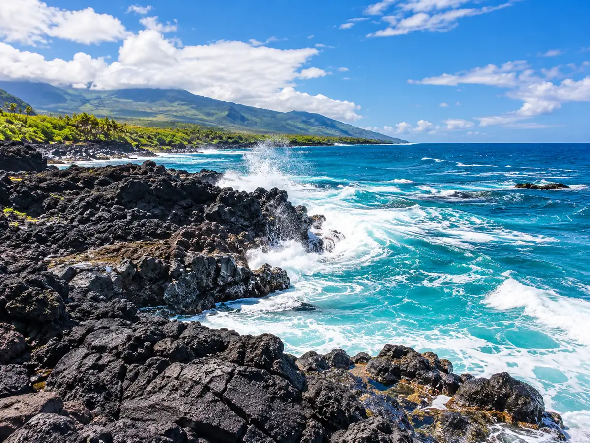 Rocce di lava nera e onde sulla costa orientale di Maui sotto un cielo drammatico